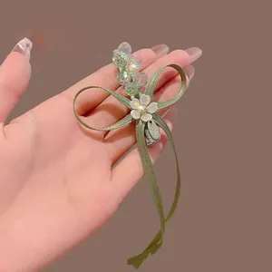 Detail einer handgefertigten hellgrünen Haarklammer mit Kristallperlen und weißer Blume