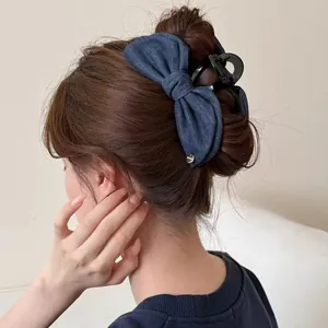 Retro dark blue denim bow hair claw clip for women shown on a model from a side back view