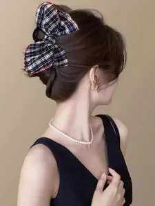 Detail of blue plaid bow hair claw clip with red stitching on a model's hair