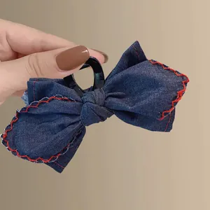 Denim bow hair claw clip with red contrast stitching and durable black plastic grip
