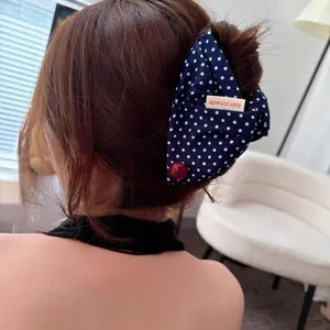Navy blue polka dot ribbon hair claw clip with handmade tag shown on model