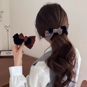Elegant two-tone bow hair clip in black velvet and brown fabric on long wavy hair