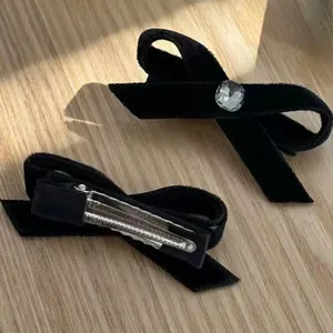 Barrettes à cheveux en velours noir avec cristal sur une surface en bois naturel