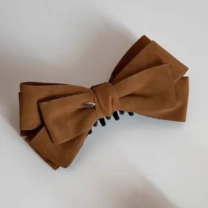 Brown suede bow banana clip with gold label for an elegant ponytail hair styling