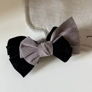 Detailed view of layered black velvet and grey-purple textured fabric bow hair clip