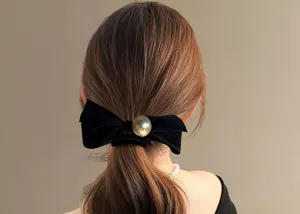 Close-up of elegant black velvet bow hair tie with large pearl detail on low ponytail