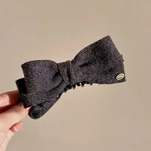 Close-up of black tweed bow hair claw clip with golden metal hardware detail