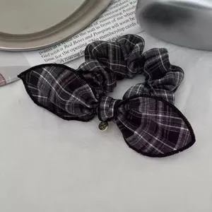 Detail of black and white plaid scrunchie with bow and gold pendant on magazine