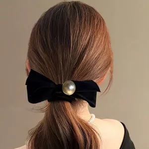 Elegant black velvet bow hair tie with a large pearl accent, styled on a ponytail back view