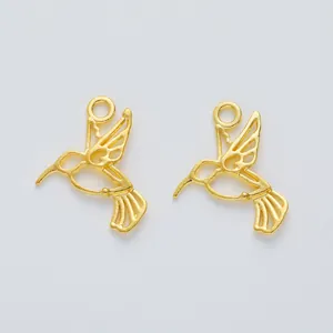 Detailed macro view of two gold-colored hummingbird alloy charms with hollow wings