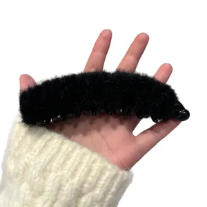 Elegante pinza de banana de pelo sintético negro sobre un fondo de punto blanco suave