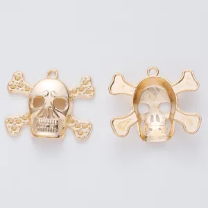 Vintage gold skull and crossbones metal pendants with embossed textures on white background