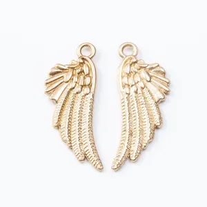 Close-up of golden alloy wing charms with textured feathers and integrated top hanging loop