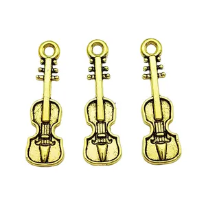 Vista detallada de tres dijes de violín de bronce vintage con textura antigua para joyería
