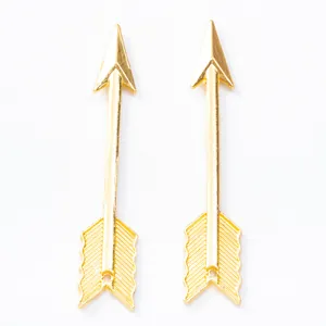Paire de pendentifs flèches vintage en alliage doré avec plumes ciselées sur fond blanc