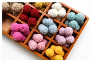 Detailed view of colorful handmade wool felt balls sorted in a wooden tray for DIY crafts
