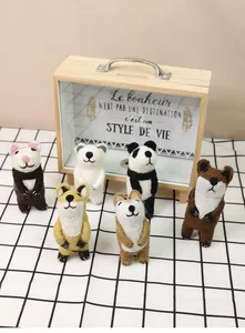 Handmade felt animals including panda and fox displayed in a rustic wooden glass case