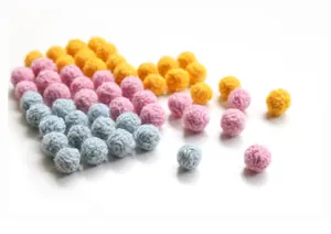 Detail of colorful wool felt balls in ginger, pink, and blue for DIY handmade crafts
