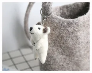 Détail d'un porte-clés souris en laine feutrée artisanale sur un panier gris