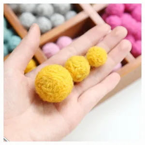 Close-up of handmade yellow wool felt balls in three sizes for DIY craft accessories