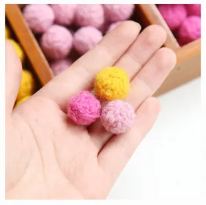 Close-up of colorful handmade wool felt balls held in palm for DIY jewelry sizing