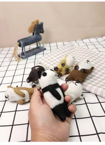 Handmade wool felt panda brooch held by hand, showing soft texture and cute animal design