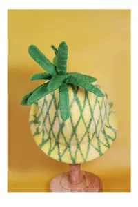 Close-up of handmade yellow wool felt pineapple hat showing thick fiber texture on wood stand