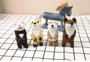 Macro shot of handmade wool felt cute panda, fox, and hamster animals on plaid fabric