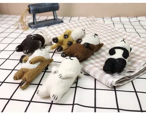 Close-up of handmade needle felted panda and fox animal brooches on a checkered fabric