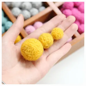 Handmade yellow wool felt balls for DIY earrings and jewelry crafts shown in hand