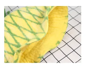 Close-up of handmade wool felt pineapple hat with yellow texture and green leaf detail