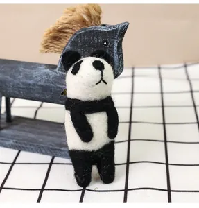 Close-up of handmade wool felt panda doll with detailed needlework texture on wood