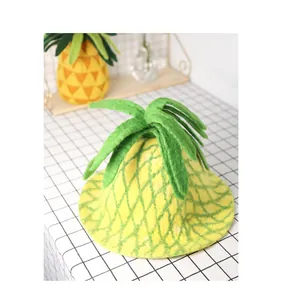 Detail shot of a handmade yellow pineapple wool felt hat with green leaf top decoration