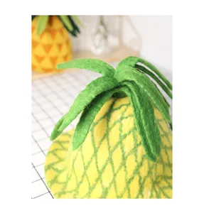 Detailed texture of handmade yellow wool felt pineapple hat with green leaf top