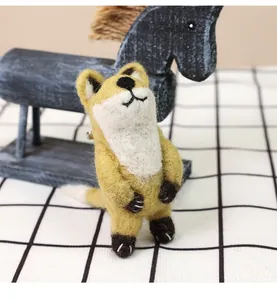 Detailed view of handmade wool felt fox brooch with black embroidery on plaid fabric