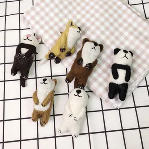 Handmade wool felt animal brooches including panda and fox on a checkered fabric