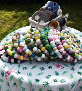 Detail of colorful handmade wool felt coasters with soft pom pom texture on a table