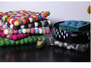 Close-up of colorful handmade wool felt ball coasters showing thick square texture