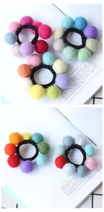 Detailed macro view of colorful handmade wool felt ball elastic hair ties on a book