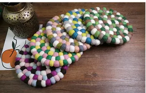 Close-up of colorful handmade wool felt ball coasters on a dark wooden table background