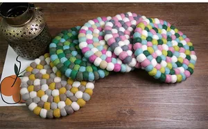 Detail of colorful handmade wool felt ball coasters on a rustic dark wood surface