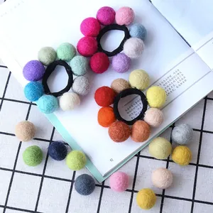 Handmade colorful wool felt ball hair ties and DIY craft beads on a stylish background