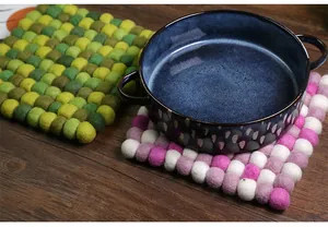 Detail of colorful handmade wool felt ball coasters in green and pink on a wooden table