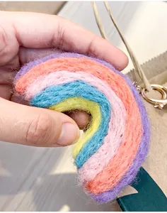 Close-up of handmade rainbow wool felt keychain charm with colorful stripes and gold ring