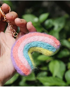 Handheld view of a colorful handmade wool felt rainbow keychain with metal chain