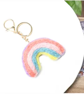 Macro detail of a handmade rainbow wool felt charm with a golden metallic keychain hook
