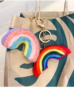 Detail of wool felt rainbow charms with golden keychains on a paper bag background