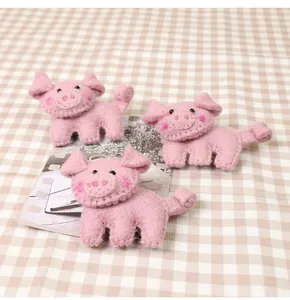Detailed close-up of handmade pink felt pig brooches with stitching and fiber texture