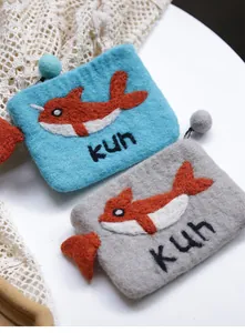 Detailed embroidery of a whale and fuzzy ball zipper on wool felt coin purses
