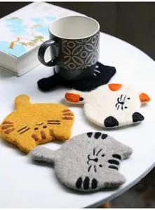 Detailed view of handmade cat wool felt coasters with embroidery and grey tea cup
